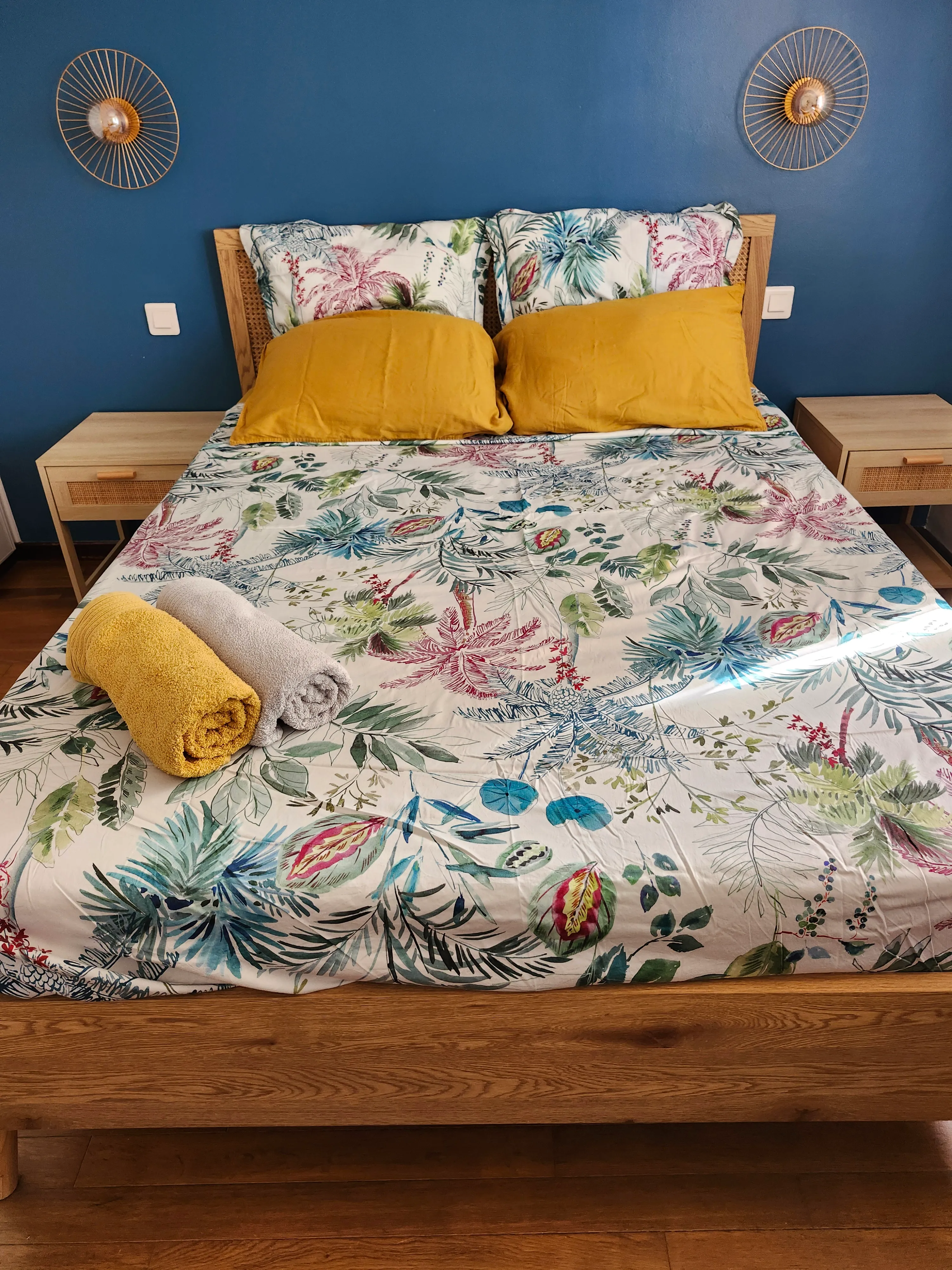 Chambre Bleu paon du gîte de Mellonia : mur bleu, lit double et parure tropicale